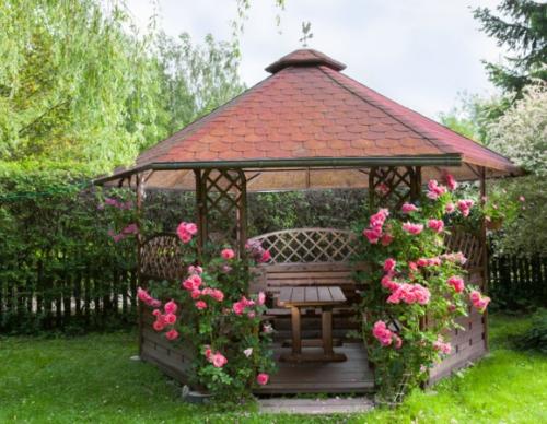 Outdoor wooden gazebo with roses and summer landscape background